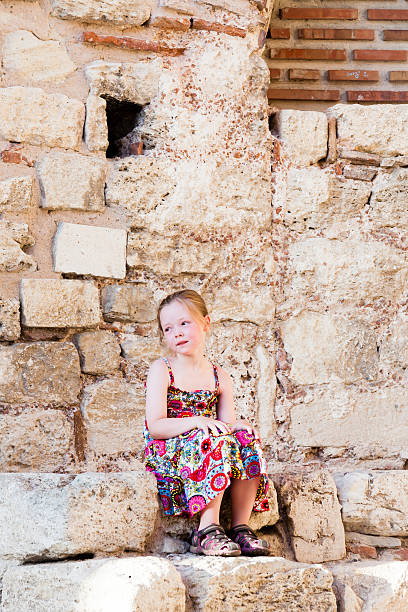 istock Girl sitting among the stones 585629848