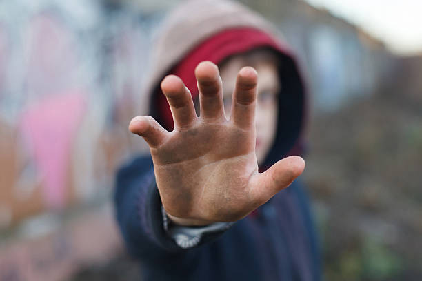dramatic portrait of a little homeless boy, dirty hand dramatic portrait of a little homeless boy, dirty hand, poverty, city, street refugee camp stock pictures, royalty-free photos & images