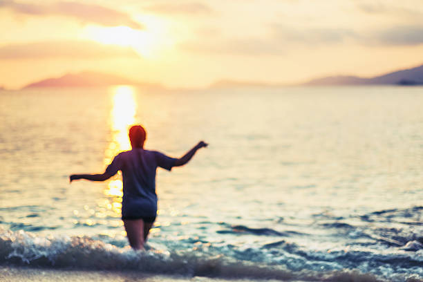 istock Blurred defocus, rear view young female walking on the beach 585764304