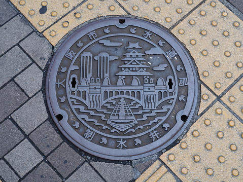 Osaka, Japan - June 08, 2016: A manhole cover in Osaka, Japan. A ship on Dotonbori canal and Osaka castle engraved on to a manhole cover as a symbol of an important city's landmark.