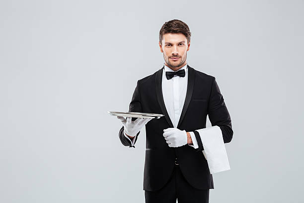 istock Attractive butler in tuxedo standing and holding silver empty tray 585768878