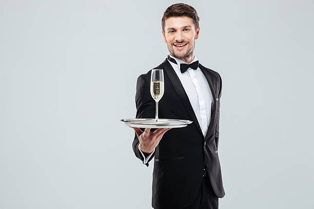 シャンパンのグラスを提供するタキシードの陽気な執事 - butler champagne service waiter ストックフォトと画像