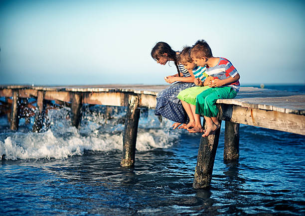 istock Kids feeding fish on sea pier 585770444