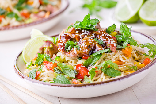 Bowl of thai noodles with pork and fresh vegetables