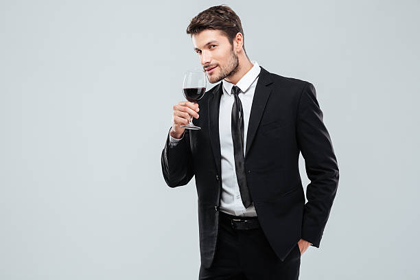 istock Attractive young businessman standing and drinking red wine 585773366