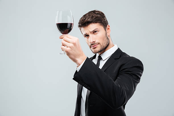 istock Man sommelier tasting and looking at red wine in glass 585773732