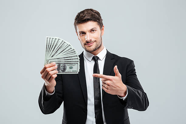 istock Attractive young businessman holding money and pointing on it 585774310