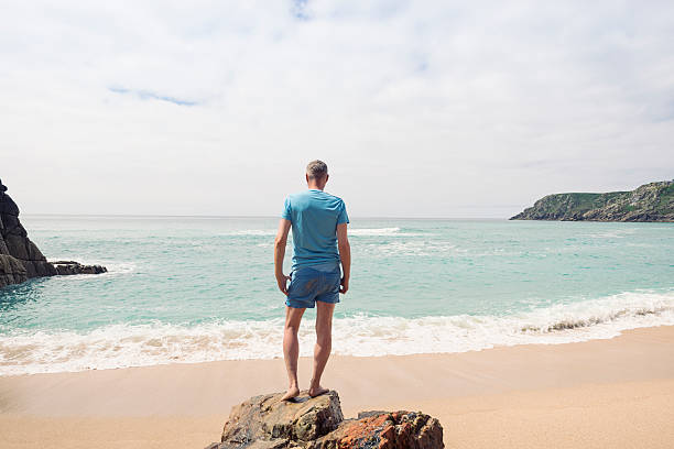 istock Man standing on a rock at Pedn Vounder Beach, Cornwall. 585777566