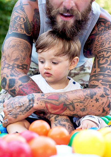 tattooed father and son playing with colored balls - tattoo father family son imagens e fotografias de stock