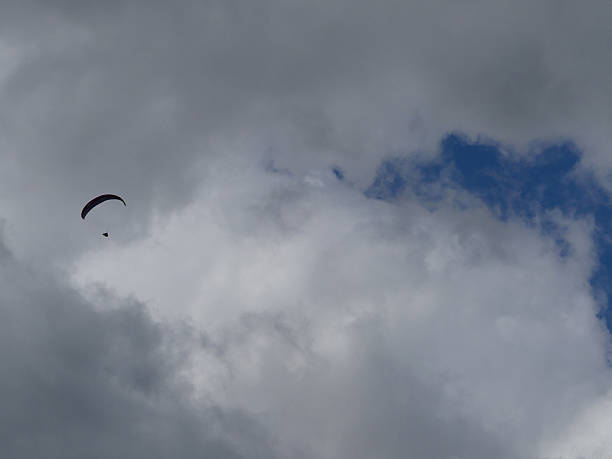 istock Paraglider against dark clouds and blue sky 585779750