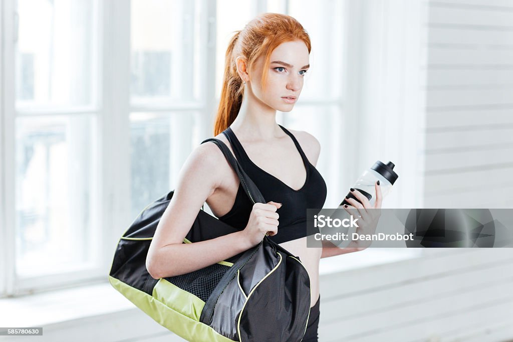 Young pretty fitness woman with sports bag and water bottle Young pretty fitness woman with sports bag and water bottle at the gym Adult Stock Photo