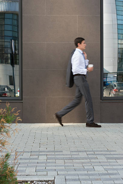 istock Side view of young businessman passing office building 585783358