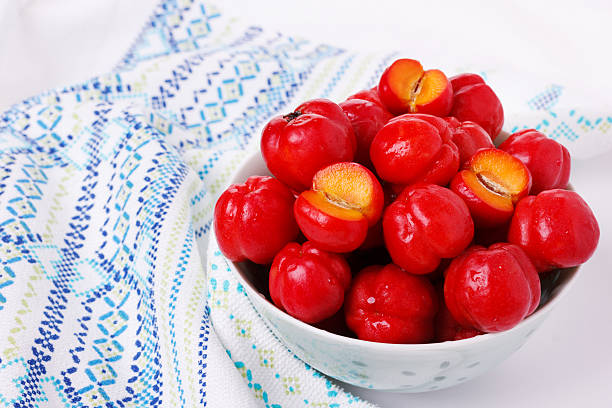Malpighia glabra (red acerola), tropical fruit in bowl on white background. Selective focus