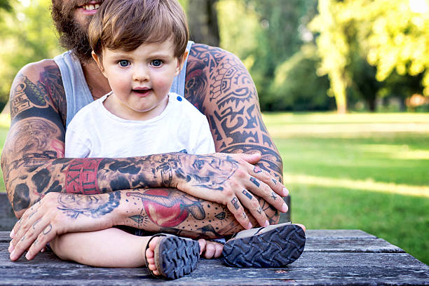 padre tatuato che abbraccia il figlio - tattoo father family son foto e immagini stock