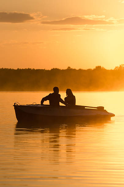istock Romantic golden river sunset. Couple on boat backlit by sunlight 585785894