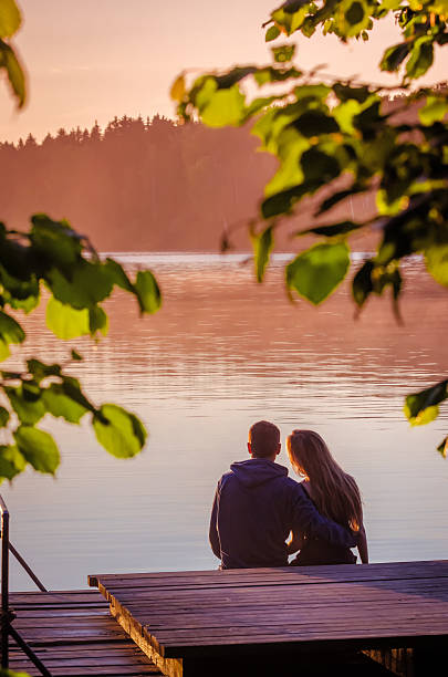 istock Romantic couple sitting on pier enjoying stunning sunset 585786002