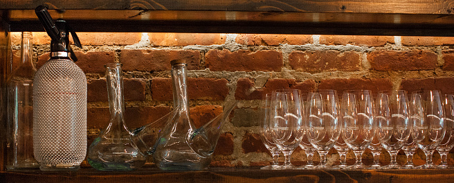 Arrange of wine glasses and water battles on the shelf brick wall.  