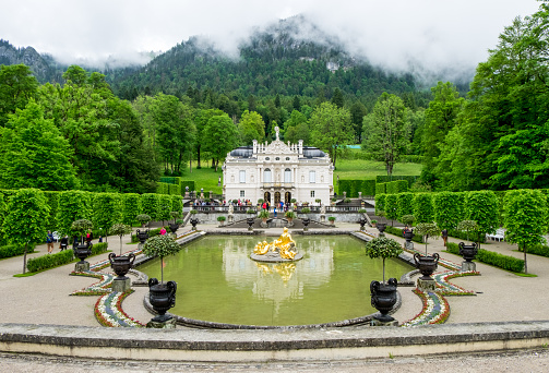 Ettal, Germany-June 11, 2016: Linderhof palace and fountain in garden, one of palace that King Ludwig II owned and finished when he was alive. Photo was shot on raining cloudy day.