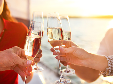 Happy friends with glasses of champagne on yacht. Vacation, travel, sea and friendship concept. Closeup.