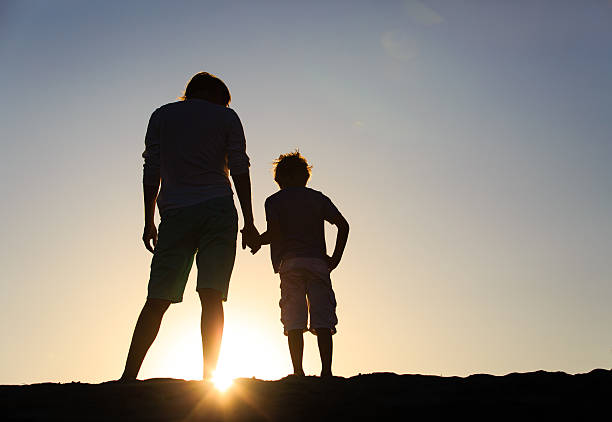 istock silhouette of father and son holding hands at sunset 585788376