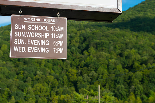 A sign outside a church provides the starting time for Sunday School, Sunday morning worship, Sunday evening worship, and Wednesday evening gathering in Carter County, Tennessee