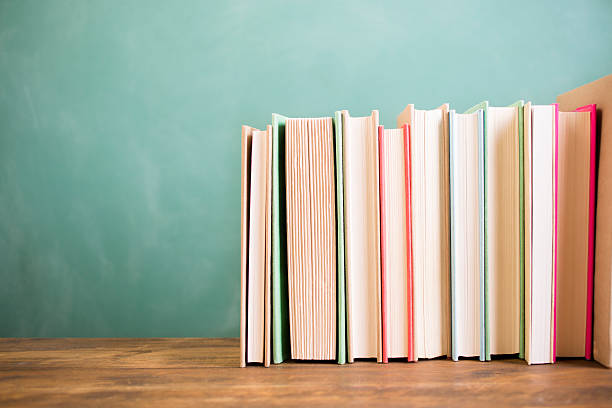 School books stacked on desk with chalkboard.