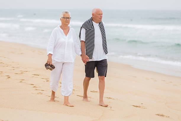 istock senior couple walking on the beach 585793760