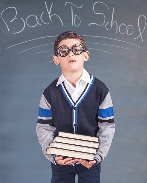 istock Nerdy little boy holding a stack of books 585794492