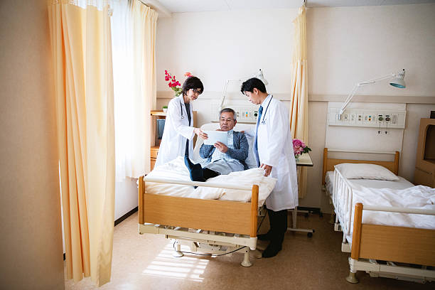 japanische arzt im gespräch mit einem patienten im krankenhaus - bed hospital prognosis patient stock-fotos und bilder