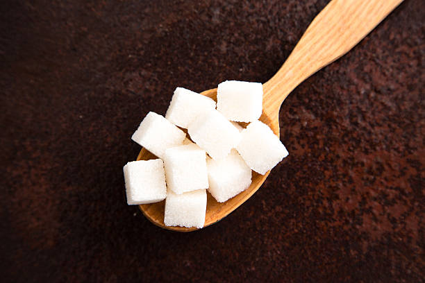 istock white Sugar cubes on the wooden spoon 585797002