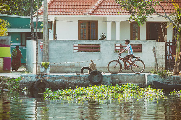 Kerala Backwaters, Kerala, India - March 12, 2015. Boy riding bicycle along the Kerala Backwaters in Kerala, India.