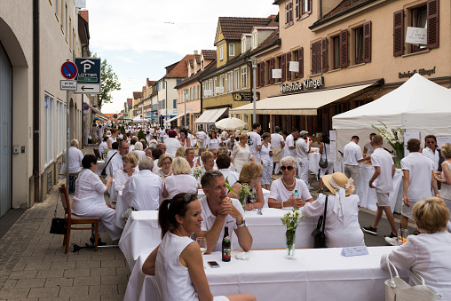 Ludwigsburg, Germany - July 30, 2016: People are enjoying le diner on blanc – the white dinner – where all guests are asked to dress in white, dining at white tables in Ludwigsburg near Stuttgart, Germany.