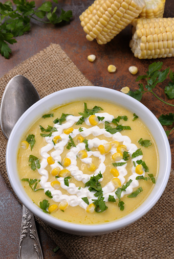 bowl of pureed soup mealies seasoned with grains of corn, parsley and sour cream