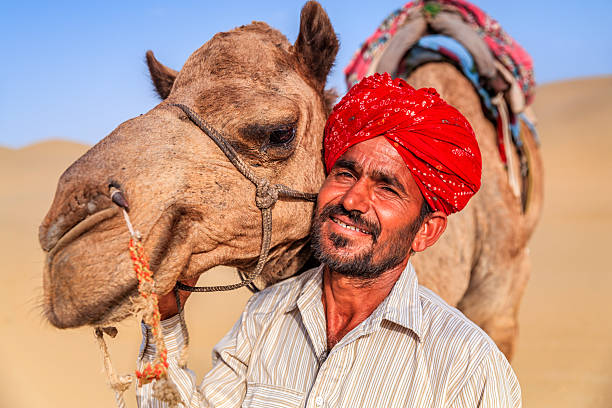 istock Indian man holding camel on sand dunes, Rajasthan, India 585805076
