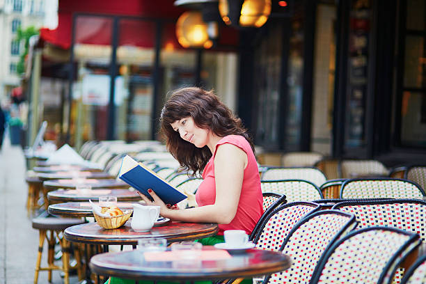 istock Girl drinking coffee and reading a book in Parisian cafe 585806770
