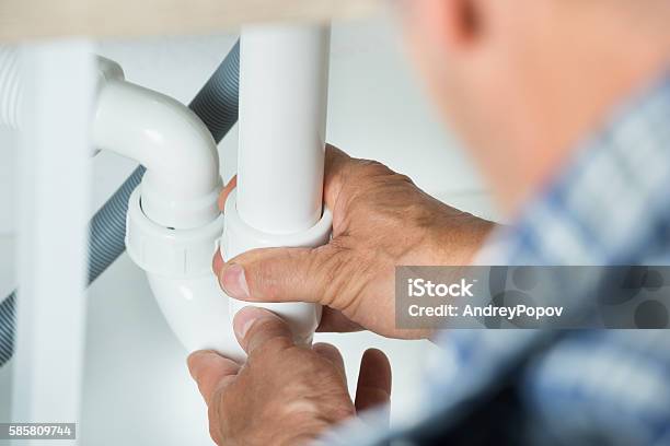 Serviceman Working On Pipes Under Kitchen Sink Stock Photo - Download Image Now - Adult, Blue-collar Worker, Expertise