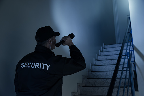 Guardia de seguridad buscando en la escalera con linterna photo