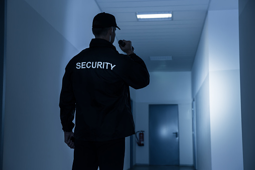 Guardia de seguridad con linterna en el pasillo del edificio photo