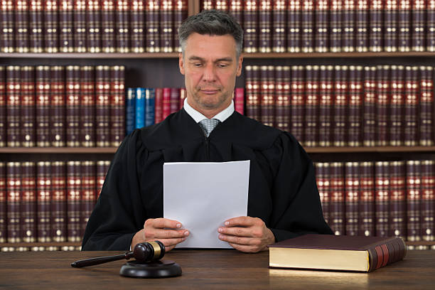 istock Judge Reading Document At Desk In Courtroom 585810556