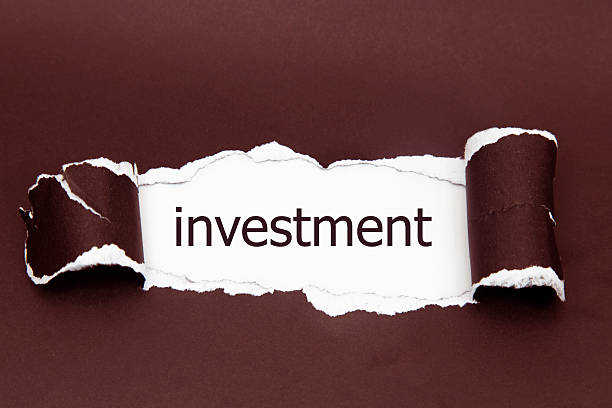 istock investment word written under torn paper. 586043808