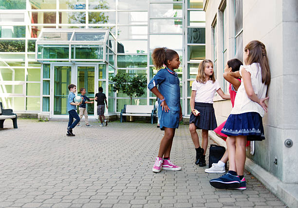 Two female nursery students walking together down the corridor. One is holding a book and they are both laughing in conversation.