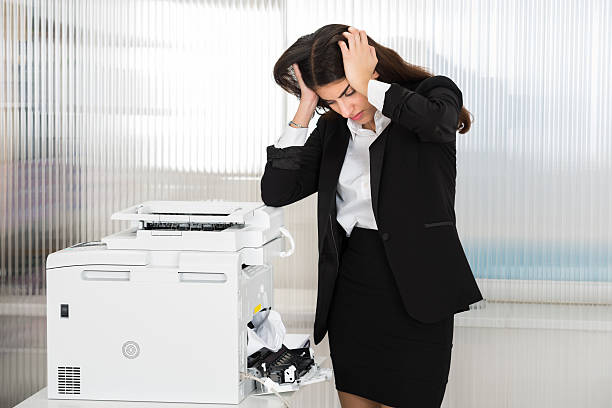 femme d’affaires irritée regardant du papier coincé dans l’imprimante - fax paper photos et images de collection