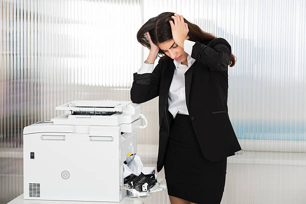 раздраженная бизнес-леди, смотря на бумагу, застрявшую в принтере - печатник стоковые фото и изображения