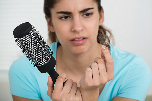 istock Woman Holding Comb While Looking At Hair Loss 586044642