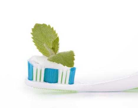Toothbrush with toothpaste and fresh leaves of mint  on a white background.
