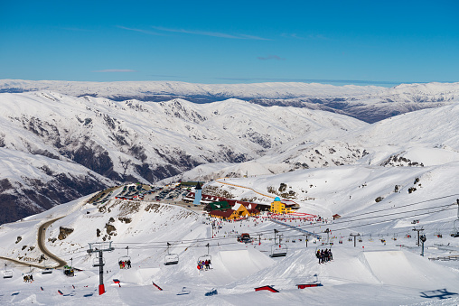 People lifting in front of Cardrona Mountain Ski Resort with plenty of snow and blue skies