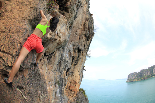 young woman rock climber climbing at seaside mountain rock