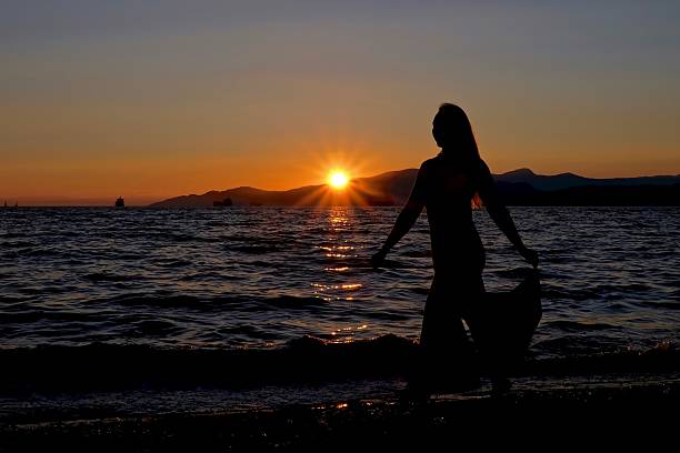 istock Young woman silhouette on sunset beach. 586048742