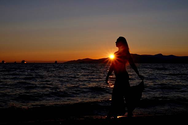 istock Young woman silhouette on sunset beach. 586048748