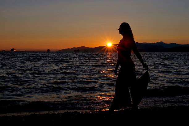 istock Young woman silhouette on sunset beach. 586048756